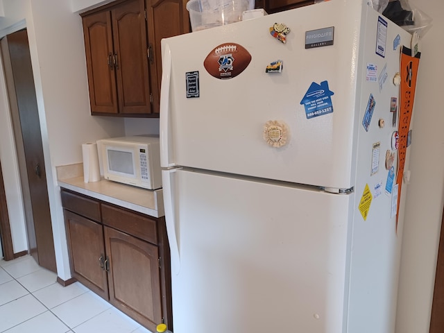 kitchen featuring white appliances, light tile patterned floors, and light countertops