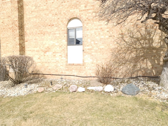 view of property exterior with brick siding and a lawn