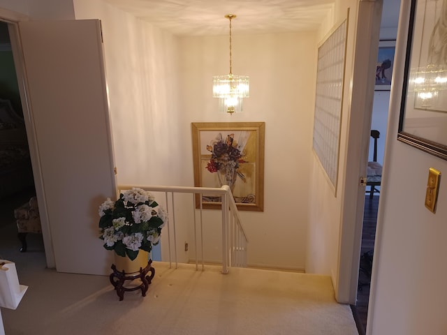 hallway with carpet, an upstairs landing, and a chandelier