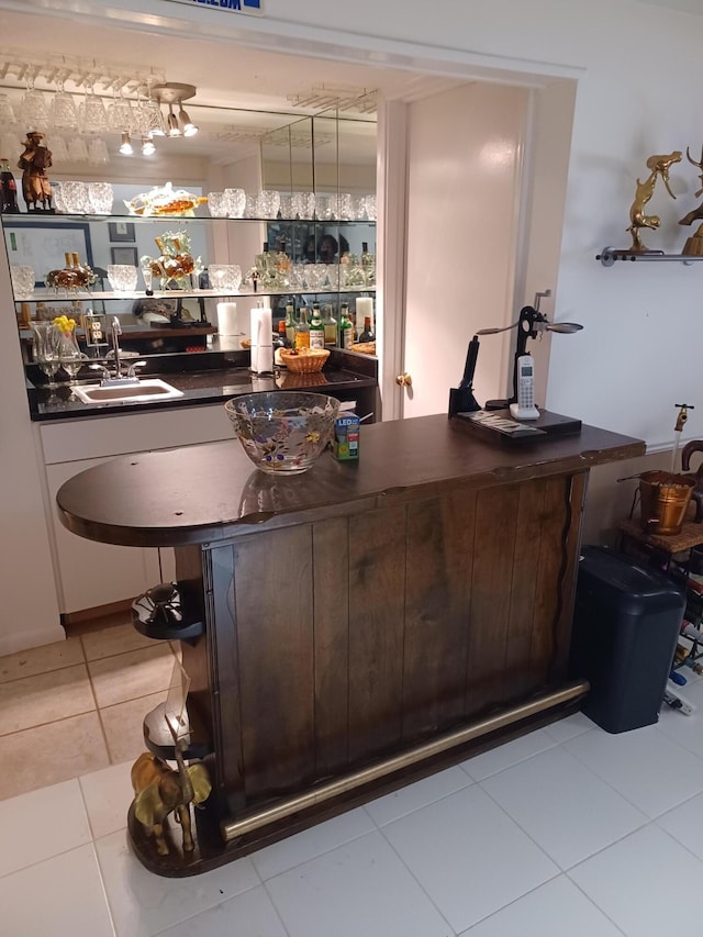 bar with light tile patterned floors and a sink