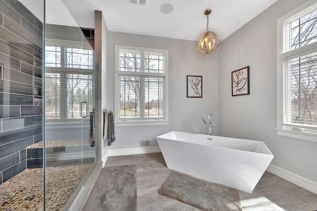 bathroom featuring visible vents, baseboards, a freestanding bath, and wood finished floors