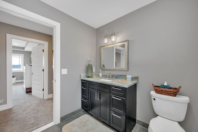 bathroom featuring toilet, baseboards, and vanity