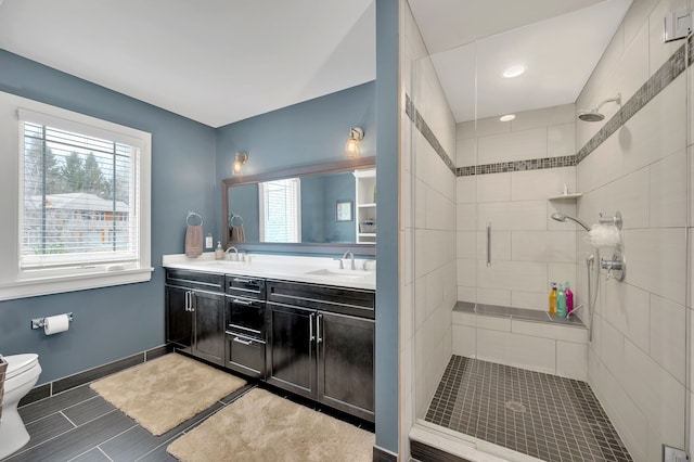 bathroom featuring a sink, a stall shower, toilet, and a wealth of natural light
