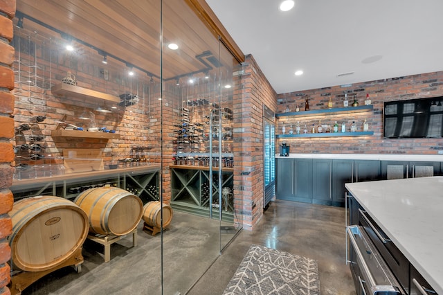 wine area featuring a bar, concrete flooring, recessed lighting, and brick wall