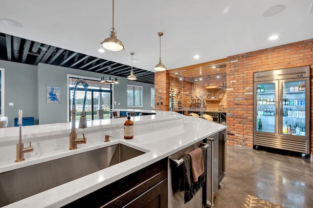 kitchen featuring finished concrete floors, a sink, brick wall, and stainless steel appliances