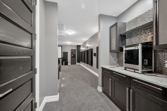 hallway featuring baseboards, a sink, and carpet flooring