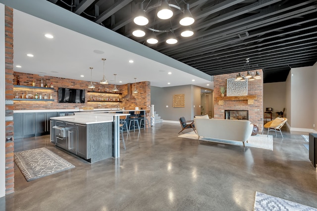 kitchen featuring light countertops, brick wall, concrete floors, gray cabinets, and baseboards