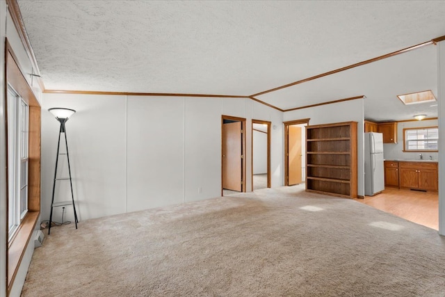 unfurnished living room with light carpet, a textured ceiling, lofted ceiling, and crown molding