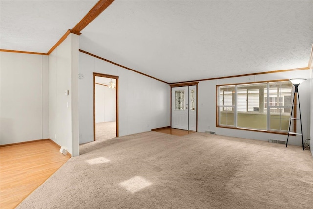 unfurnished living room featuring visible vents, lofted ceiling, and crown molding