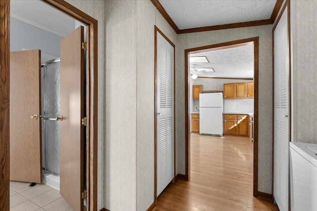 hall featuring light wood-type flooring, washer / dryer, a textured ceiling, and crown molding