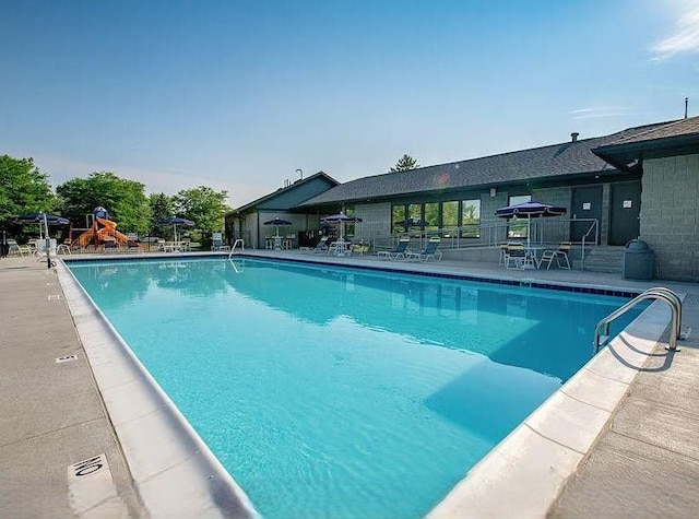 pool with a patio area and playground community