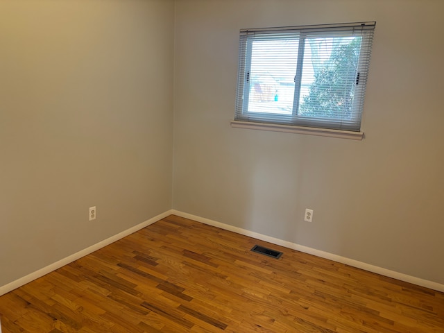 spare room with visible vents, baseboards, and wood finished floors