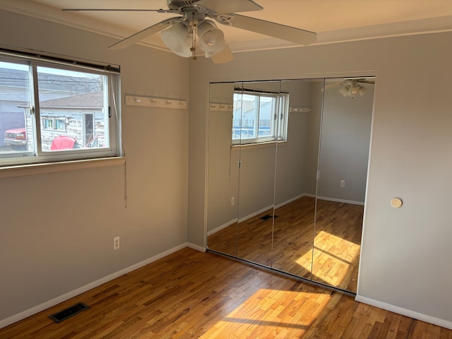 unfurnished bedroom with visible vents, baseboards, a closet, and wood finished floors