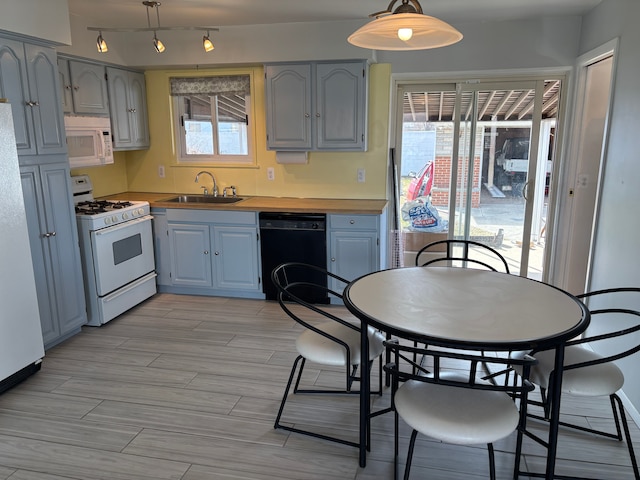 kitchen with wood tiled floor, gray cabinets, hanging light fixtures, white appliances, and a sink