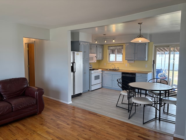 kitchen featuring a sink, white appliances, light wood-style flooring, and gray cabinetry