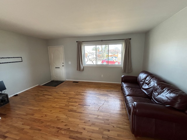 living room with visible vents, baseboards, and wood finished floors