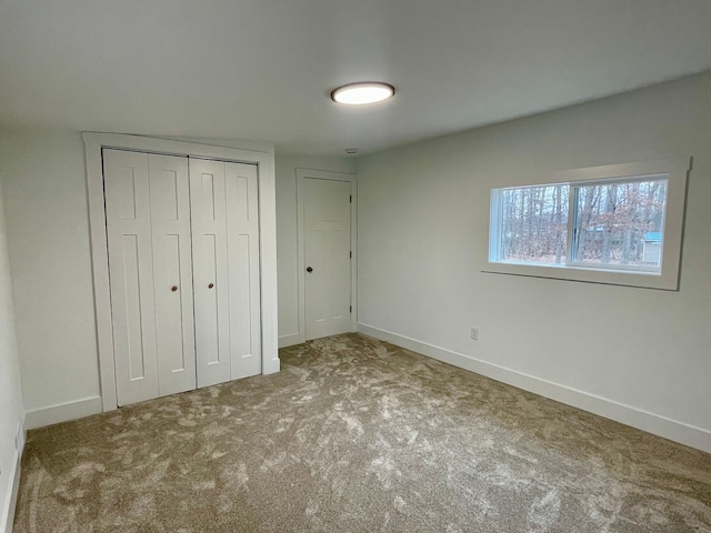 unfurnished bedroom with a closet, carpet flooring, and baseboards