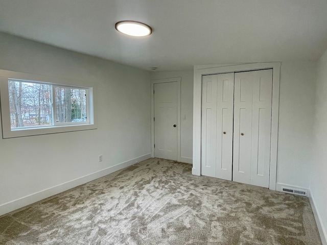 unfurnished bedroom with a closet, baseboards, visible vents, and carpet floors