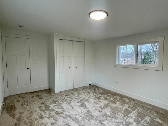 unfurnished bedroom with a closet, carpet floors, baseboards, and visible vents