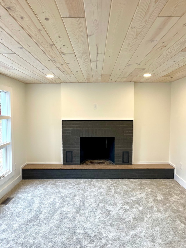 unfurnished living room with a fireplace, wood ceiling, visible vents, and carpet floors