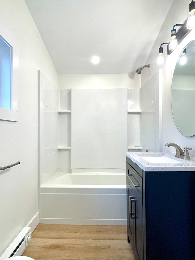 bathroom with vanity, washtub / shower combination, a baseboard heating unit, and wood finished floors