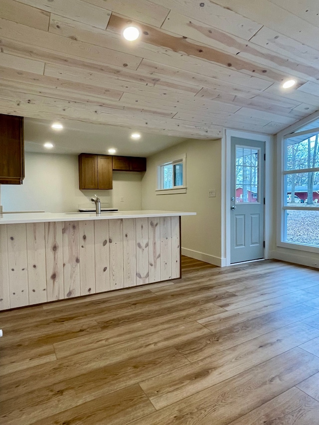 kitchen featuring a sink, light wood-style floors, wooden ceiling, light countertops, and baseboards