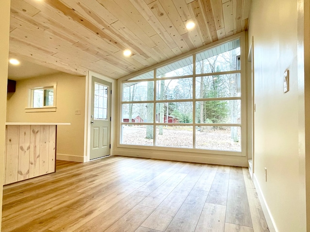 interior space with light wood finished floors, a healthy amount of sunlight, wood ceiling, and vaulted ceiling