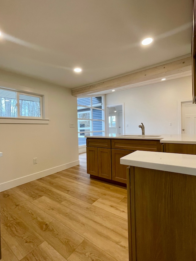 kitchen featuring light countertops, recessed lighting, light wood-type flooring, and a sink