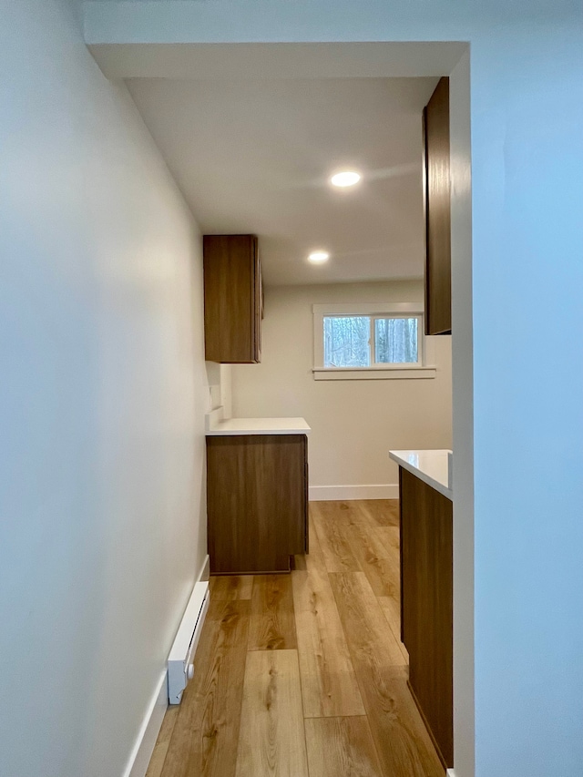 hall with recessed lighting, light wood-type flooring, a baseboard heating unit, and baseboards