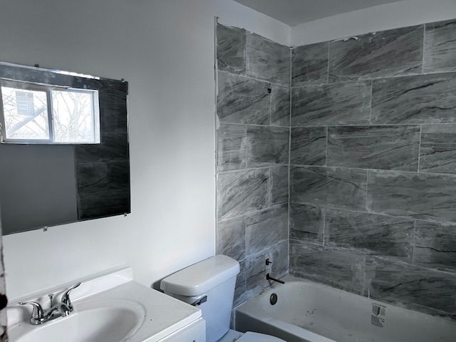 bathroom featuring toilet, shower / washtub combination, and vanity