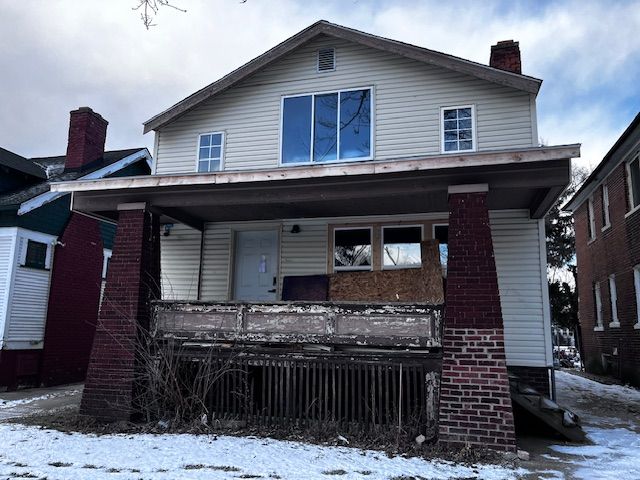 snow covered rear of property with a porch