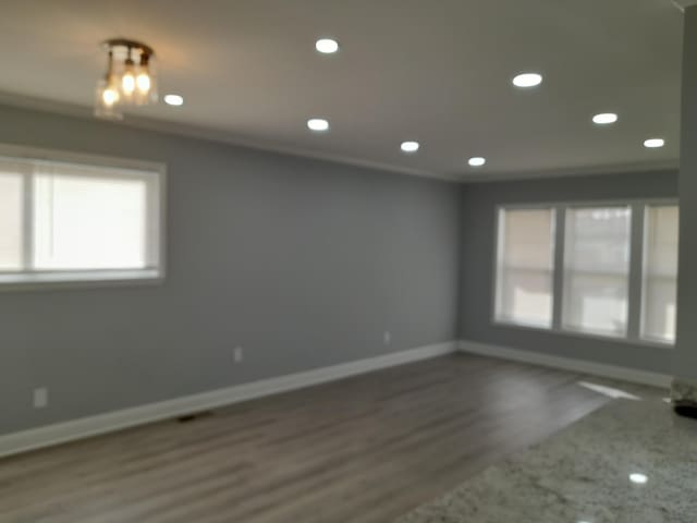 spare room with recessed lighting, ornamental molding, baseboards, and wood finished floors