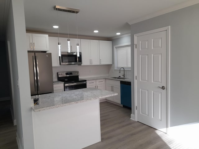 kitchen featuring ornamental molding, a sink, wood finished floors, stainless steel appliances, and white cabinets