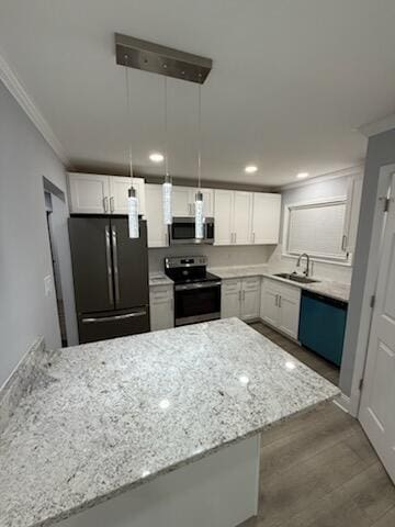 kitchen with crown molding, light stone counters, appliances with stainless steel finishes, a peninsula, and a sink