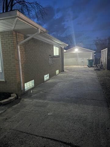 view of side of property featuring concrete driveway, brick siding, and an outdoor structure