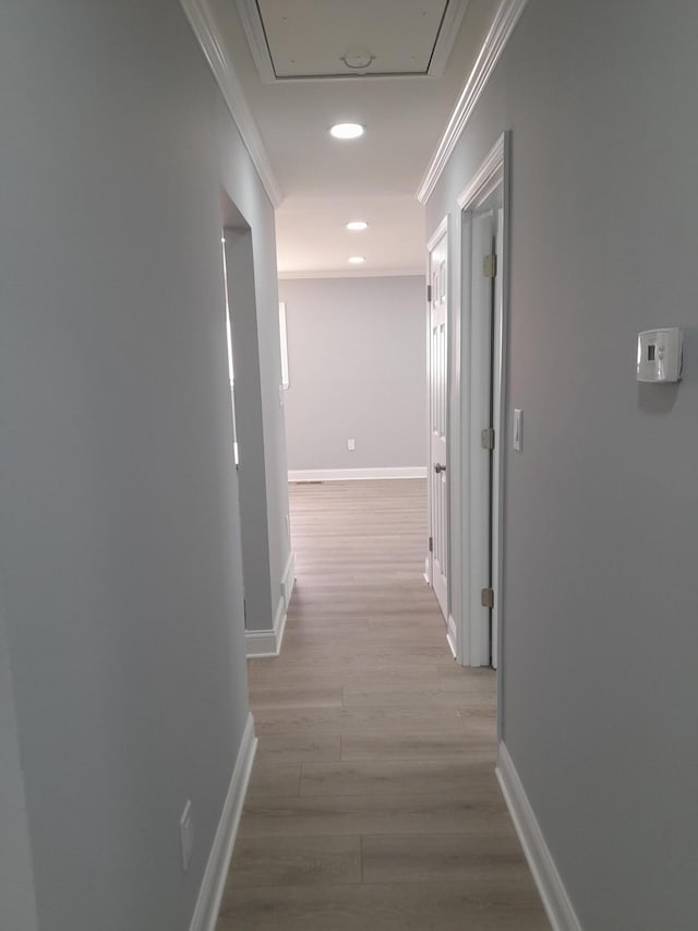 hallway with baseboards, attic access, light wood-style floors, and ornamental molding