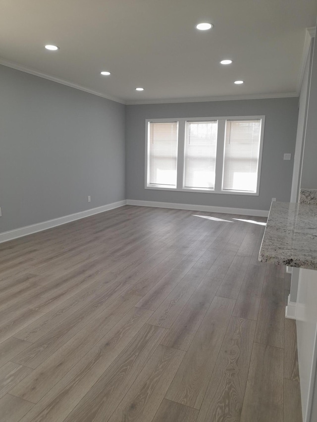 unfurnished living room with recessed lighting, wood finished floors, baseboards, and ornamental molding