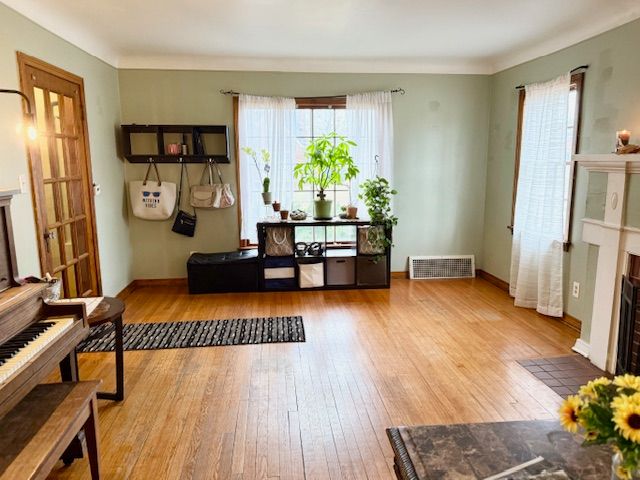 2126 Pierce St, Flint, MI 48503 - living area with baseboards, visible vents, a fireplace with flush hearth, and hardwood / wood-style flooring