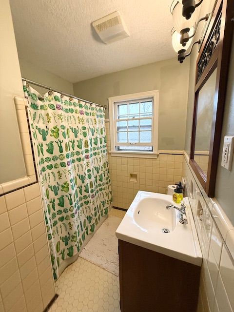 2126 Pierce St, Flint, MI 48503 - full bath featuring vanity, wainscoting, a shower with shower curtain, and tile walls