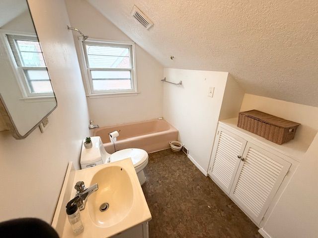 2126 Pierce St, Flint, MI 48503 - full bath featuring a textured ceiling, plenty of natural light, a washtub, vaulted ceiling, and visible vents