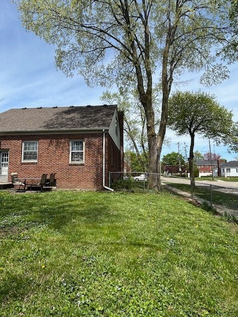 2126 Pierce St, Flint, MI 48503 - view of side of property featuring brick siding, a fenced backyard, and a lawn