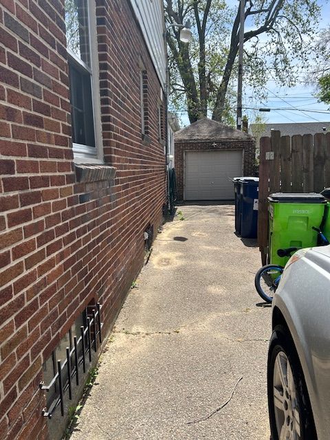 2126 Pierce St, Flint, MI 48503 - view of property exterior with a garage, fence, brick siding, concrete driveway, and an outbuilding