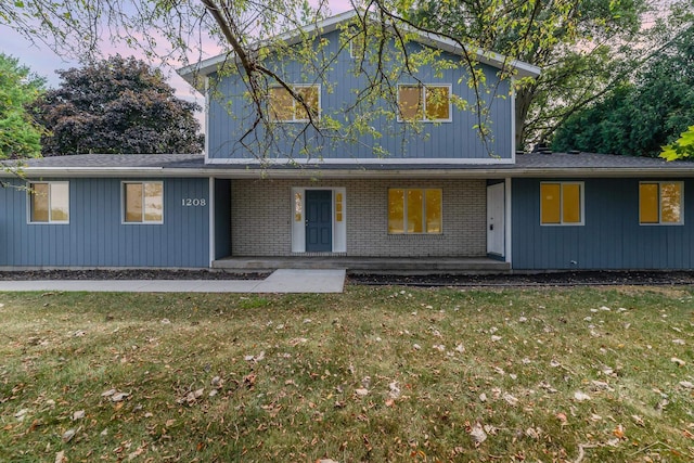 traditional home featuring brick siding, a porch, and a front lawn