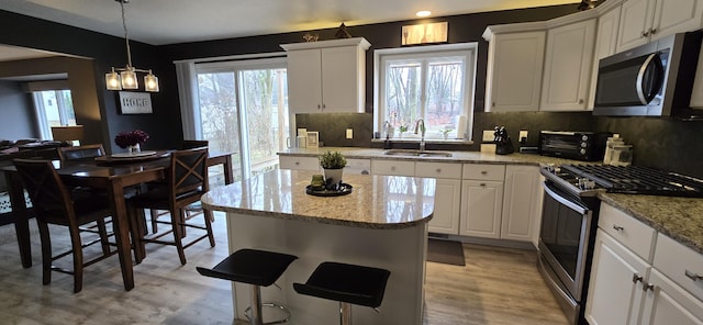 kitchen with a sink, white cabinets, a kitchen island, and stainless steel appliances