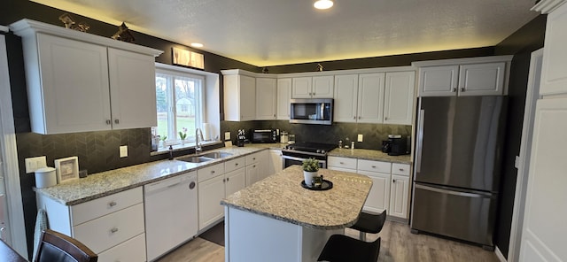 kitchen with a sink, light wood-style flooring, white cabinetry, and stainless steel appliances