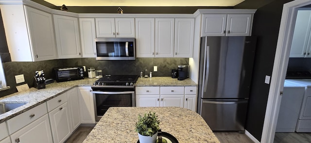 kitchen with appliances with stainless steel finishes, white cabinets, and a toaster