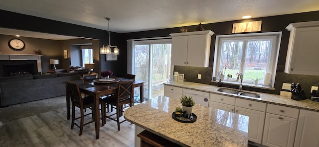 kitchen with white cabinets, white dishwasher, light wood finished floors, and a sink