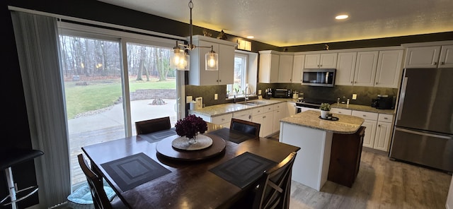 kitchen with a center island, white cabinetry, stainless steel appliances, and a sink