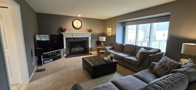 living area with a fireplace with flush hearth, carpet flooring, a textured ceiling, and baseboards