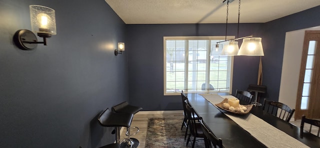 dining area with wood finished floors, baseboards, and a textured ceiling